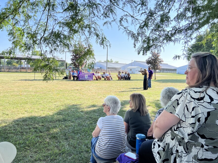 A sharpshooting competitor takes her place on a field at Darke County Fairgrounds. Audience members watch in anticipation during the "Miss Annie Oakley" shootout.