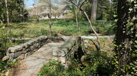 A stone bridge and wooded area in Fisher Park. 