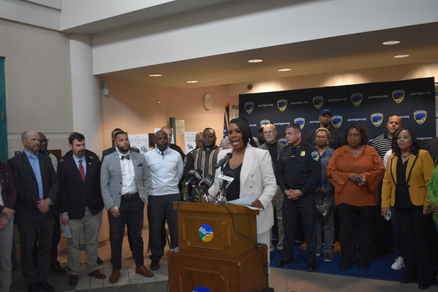 State Rep. Jehan Gordon-Booth (D-Peoria) surrounded by stakeholders at a Peoria Police Department press conference touting state public safety dollars for Peoria.