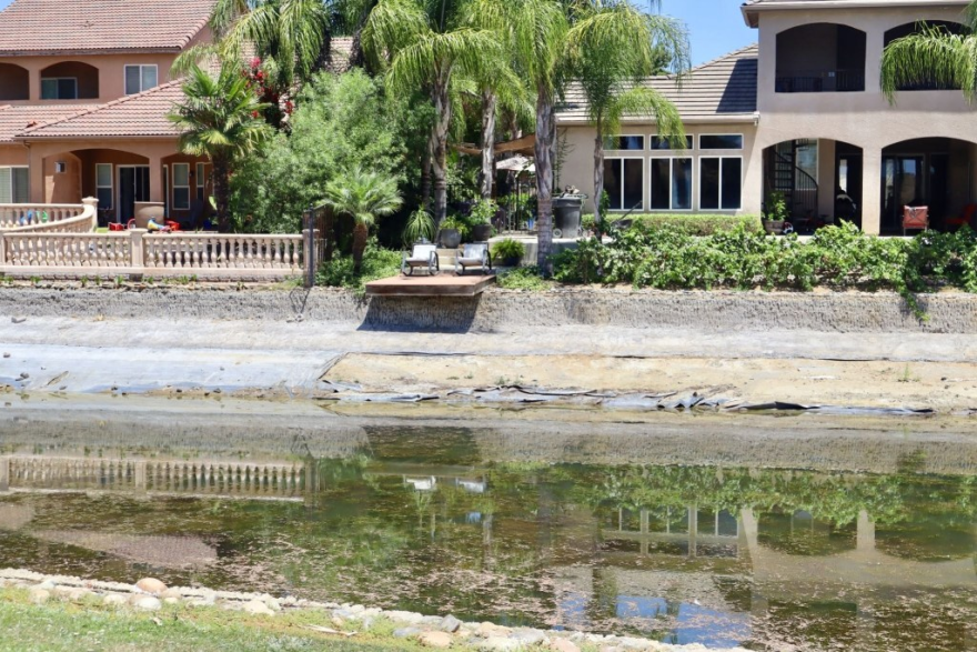 A floating wooden dock along one of the lakes in Greenhills Estates sits stranded on July 17, 2026 as water levels continue to decline. Algae covers much of the remaining water.