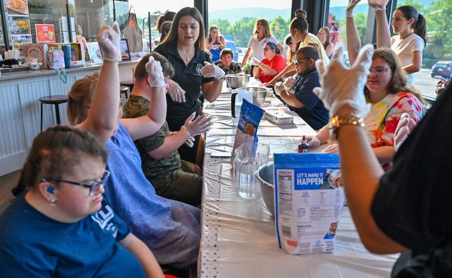 Cooking class participants raise their hands to show they are wearing gloves.