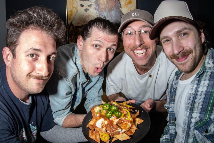 Post Sex Nachos members — guitarist Mitch Broddon, drummer Hunter Pendleton, bassist Chase Mueller and lead singer Sammy Elfanbaum — pose with a plate of their namesake, courtesy of The University Library Cafe in Des Moines.