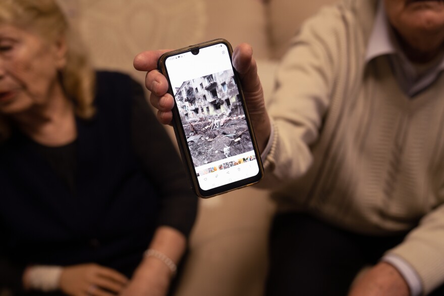 Viktor shows a photo of the damaged building where he and his wife used to live.