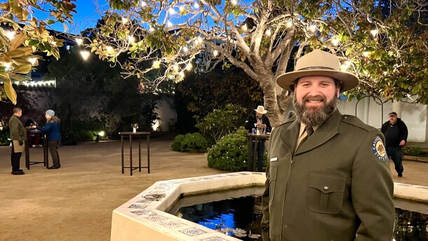 A man in a green state parks uniform smiles and looks at the camera. 