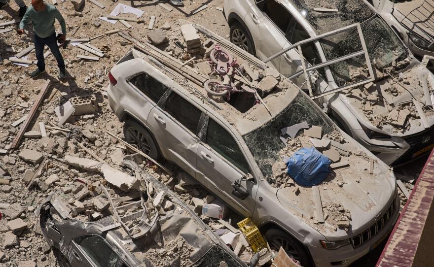 A man inspects the damage to cars and an apartment building struck by an Iranian missile in Ramat Gan, Israel, Monday, April 6, 2026. (AP Photo/Oded Balilty)