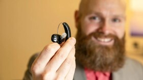 A man displays a hearing aid. Beltone is accepting nominations for free devices through its holiday giveaway program.