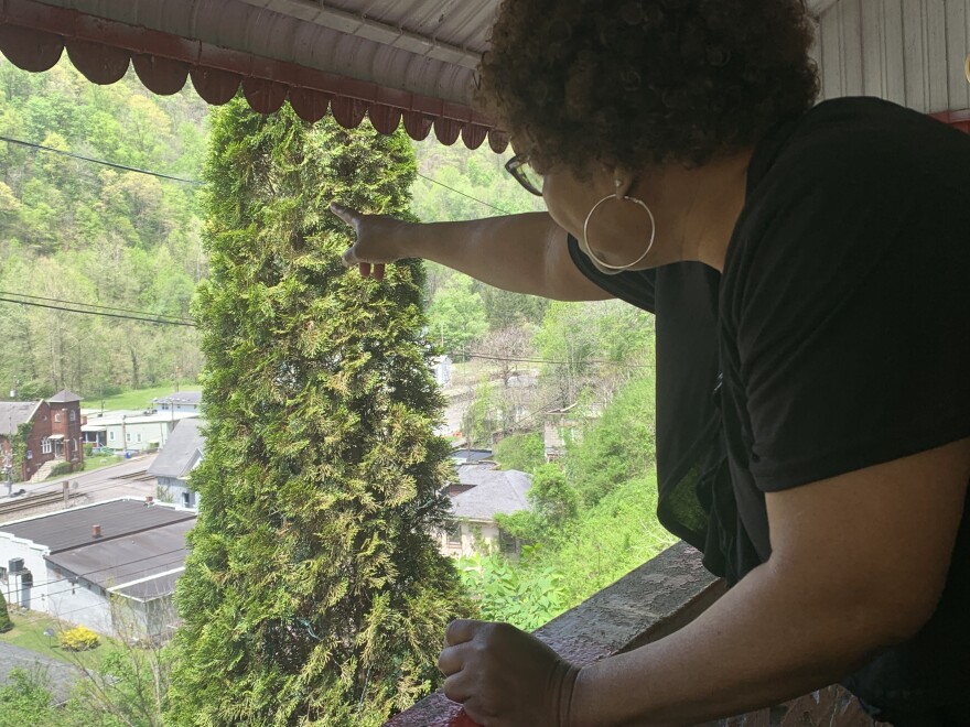 Hattie Avery points past bushes to old union hall in keystone.jpg