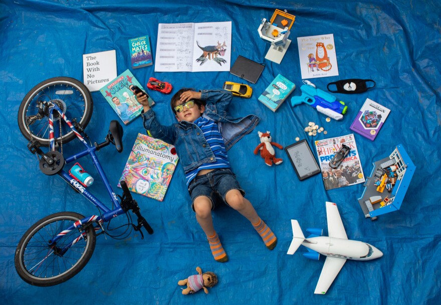 Elizabeth Dalziel's son Joe, 7, lays next to his favorite objects, toys and books as part of a homeschooling assignment — to create a time capsule — from his school in Berkhamsted, England.