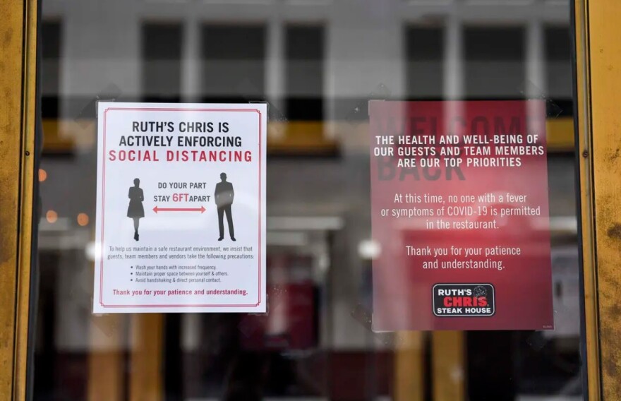 Signs posted on the door of Ruth's Chris Steak House in Austin outline the restaurant's social distancing guidelines.