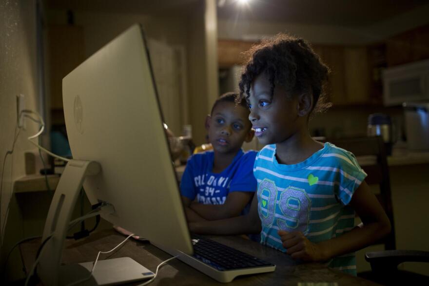 Tracie Ervin's son Michael Jr., 7, and daughter, Logan, 8, play a game that helps them practice typing speed and accuracy after school.