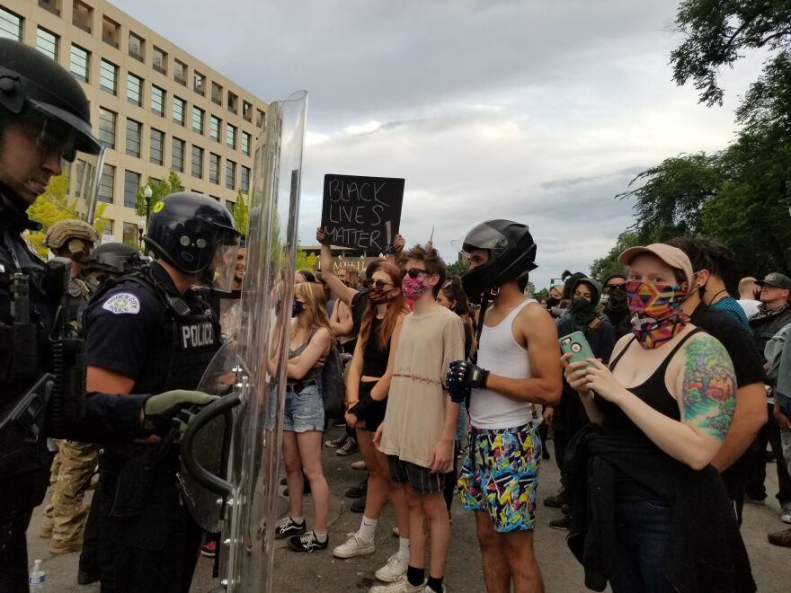 A photo of protestors facing riot police. 