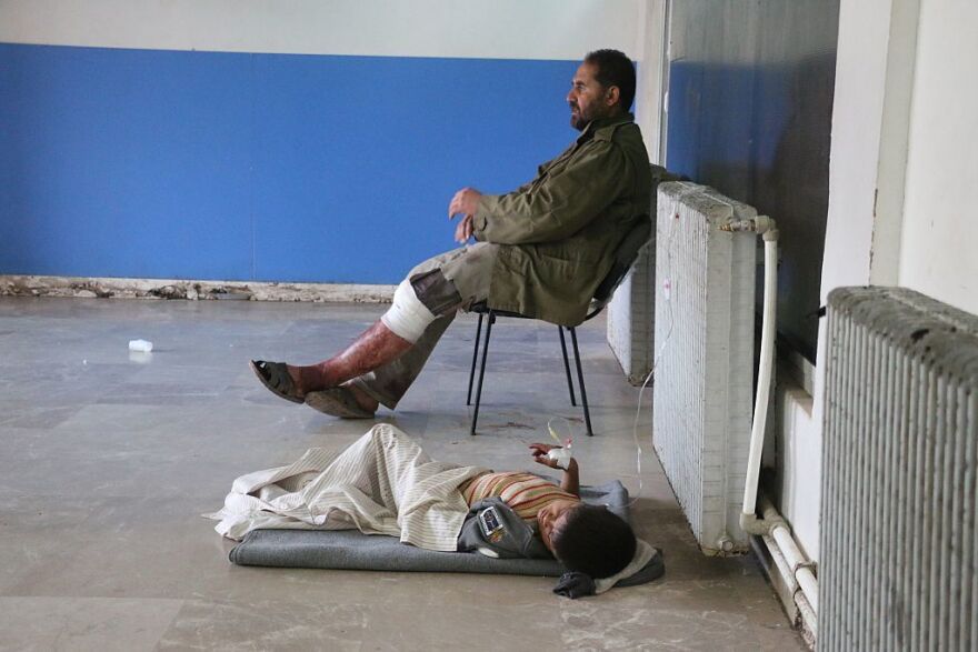 An injured man sits on a chair and a child lies on the floor as they receive medical treatment at a field hospital after an airstrike hit a refugee camp in Syria's Idlib province.