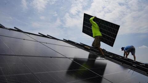 Nicholas Hartnett, owner of Pure Power Solar, carries a panel as he and Brian Hoeppner, right, install a solar array on the roof of a home in Frankfort, Ky., Monday, July 17, 2023. (Michael Conroy/AP)