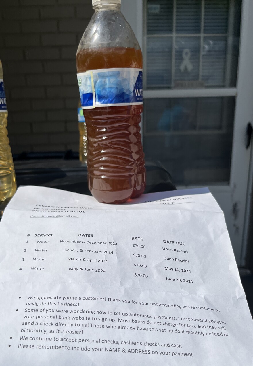 An opaque bottle of Colonial Meadows tap water and a bill for water service.