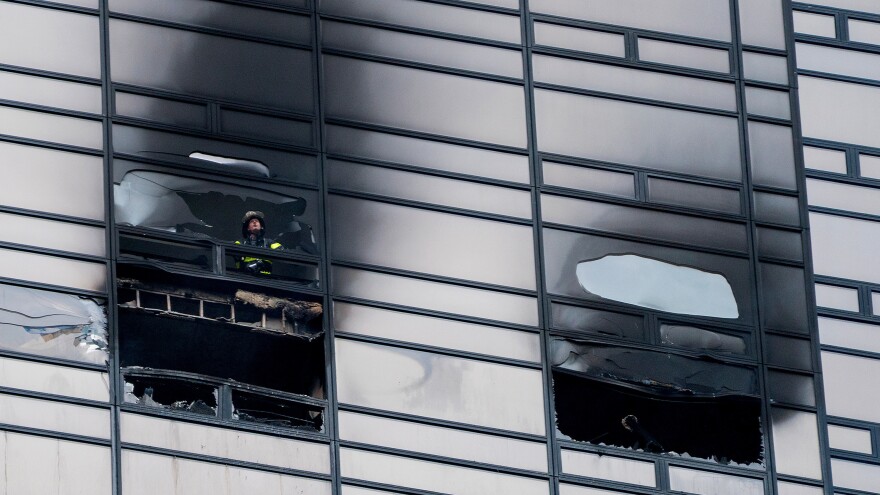 A firefighter looks out from the window of a damaged apartment in Trump Tower in New York on Saturday.