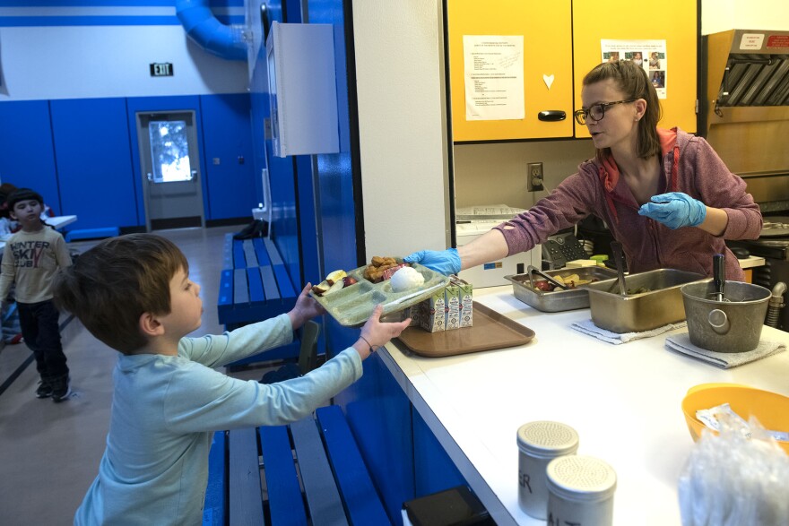 Dani Koschak passes a hot lunch to a student at Moose Pass School.