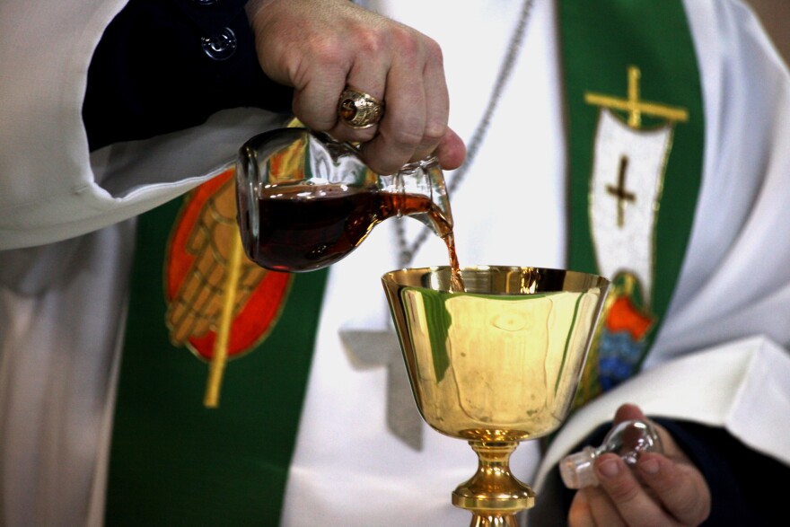 Priest pours wine into a chalice