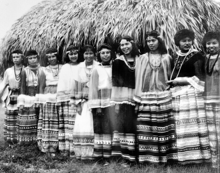 Seminole women wear patchwork skirts in an archival image.