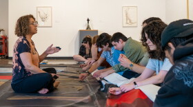 Iranian artist Minoo Emami (left) guides volunteers through the process of stitching together a quilt of her artwork to be burned Veteran's Day next month. “I love my paintings, you know, don't take me wrong,” said Emami. “But compared to veterans, veteran’s families, and what they lose? It's nothing.”