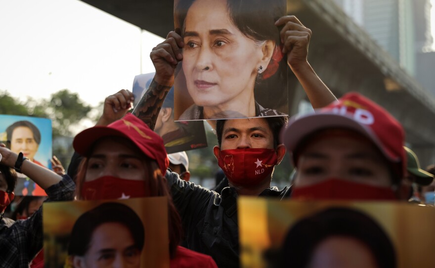 People hold up images of Myanmar's de facto leader Aung San Suu Kyi at a protest outside Myanmar's embassy in Bangkok.