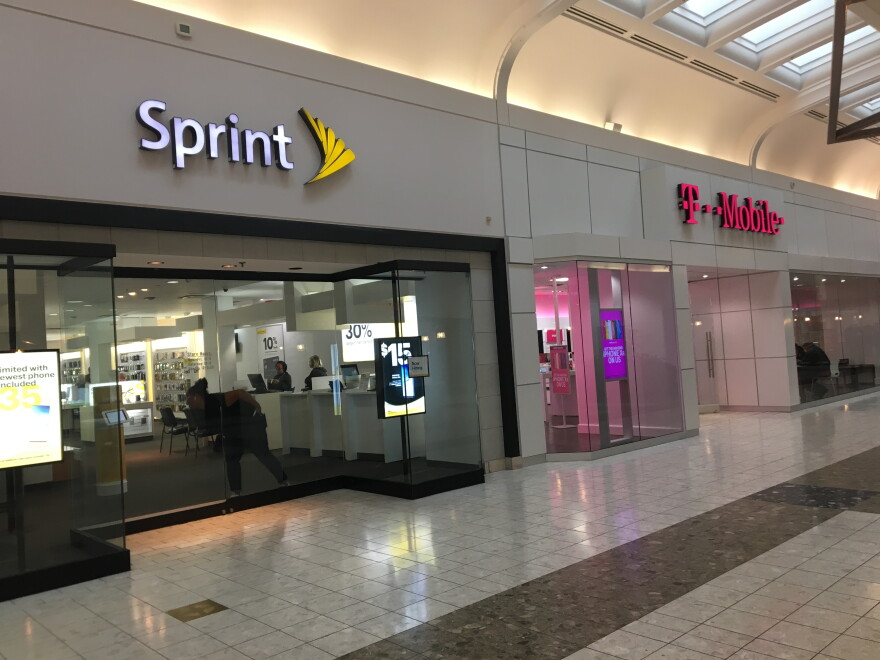 A worker locks the doors at the Sprint stores at Ward Parkway Center in Kansas City late on a Sunday in April. If a proposed merger is approved, the store's neighbor, T-Mobile, will take top billing. 