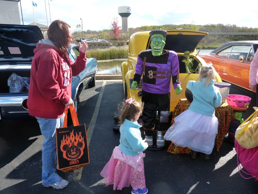 A family plucks candy from one of the cars at the "trunk or treat" event in New Berlin, Wis.