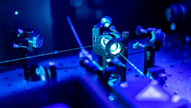 Laser reflects on optic table in quantum laboratory.