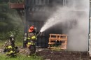 two firefighters hold a hose that is shooting water towards a burning structure