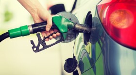 A man pumps gasoline fuel into a car at a gas station