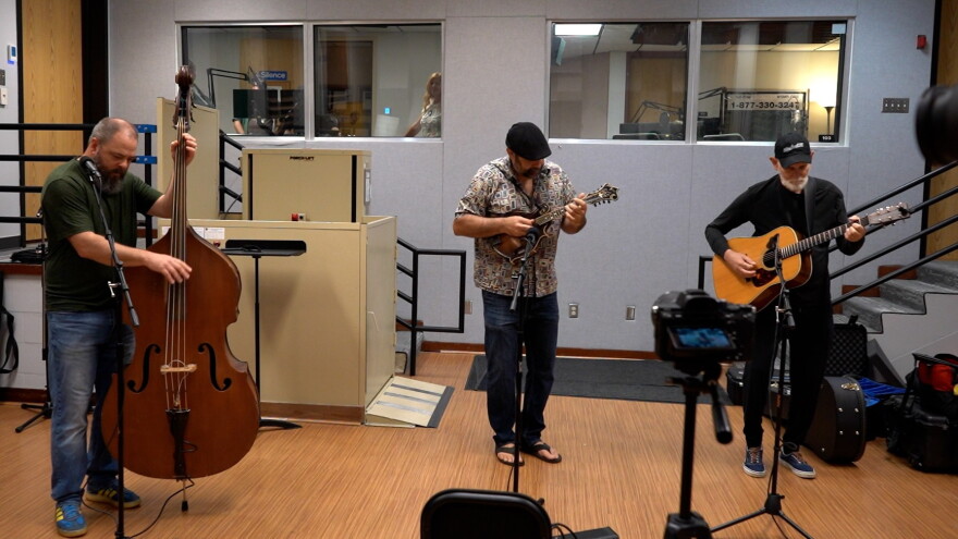 musical trio playing upright bass fiddle, mandolin and acoustic guitar in a radio studio performing 