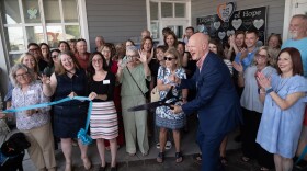 Lost & Found celebrates the unveiling of the Legacy of Hope wall with a ribbon cutting. Executive Director Mark Miller cuts the ribbon and co-founder Karen Scott stands to his right.