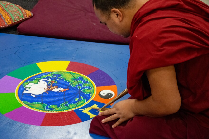 One monk works on adding the ten religious symbols representing various religions around the world to the mandala on Tuesday. Once completed, various parts of the mandala will symbolize working together and peacefulness.