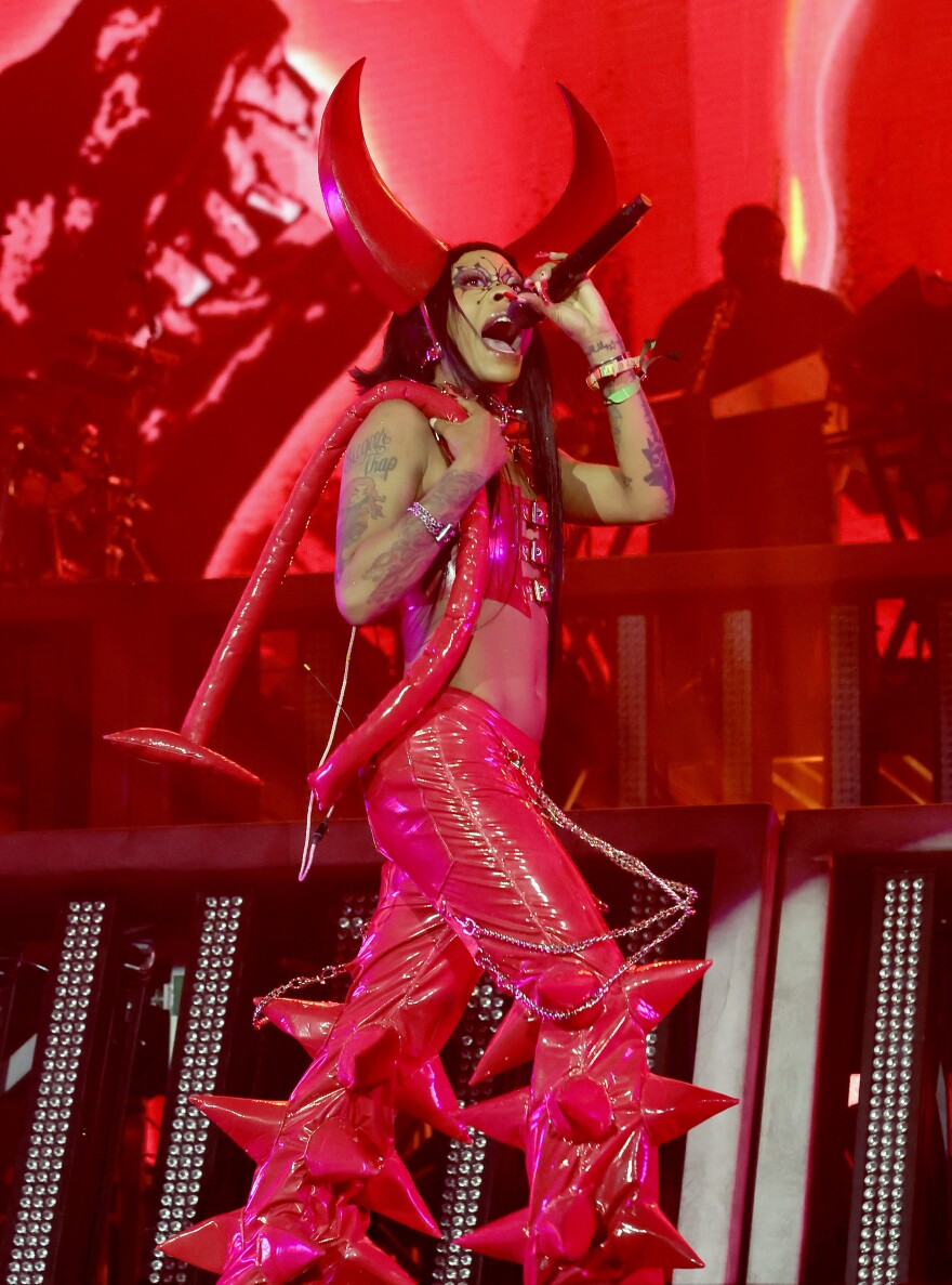 A woman on stage in a devil-like outfit singing into a microphone.