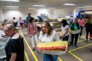 Workers handling U.S. Postal Service trays full of ballots.