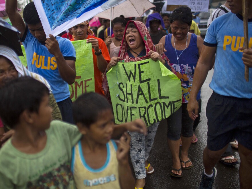 Some people marched in the rain Tuesday in the Philippine city of Tacloban, which was crushed by Typhoon Haiyan.