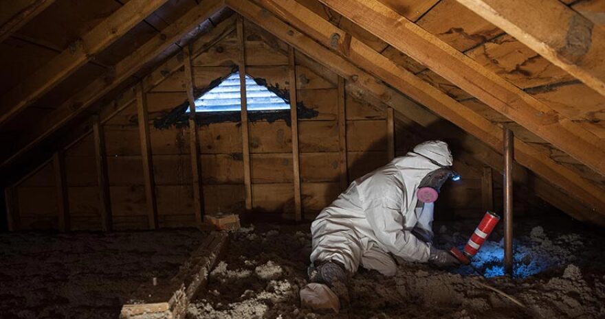 Worker insulating an attic as part of weatherization of a home.