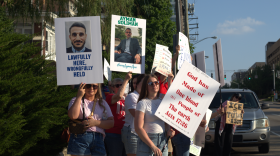 A group of people holding signs with messages of support like "Lawfully here, wrongfully held"