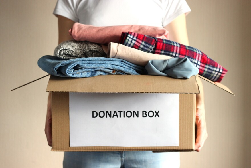 person holds a box with clothing donations