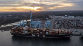 The sun sets behind The Mediterranean Shipping Company ship MSC Meline, front, which is in the process of being loaded at the Virginia International Gateway Marine terminal Wednesday Dec 1, 2021, in Norfolk, Va. (AP Photo/Steve Helber)