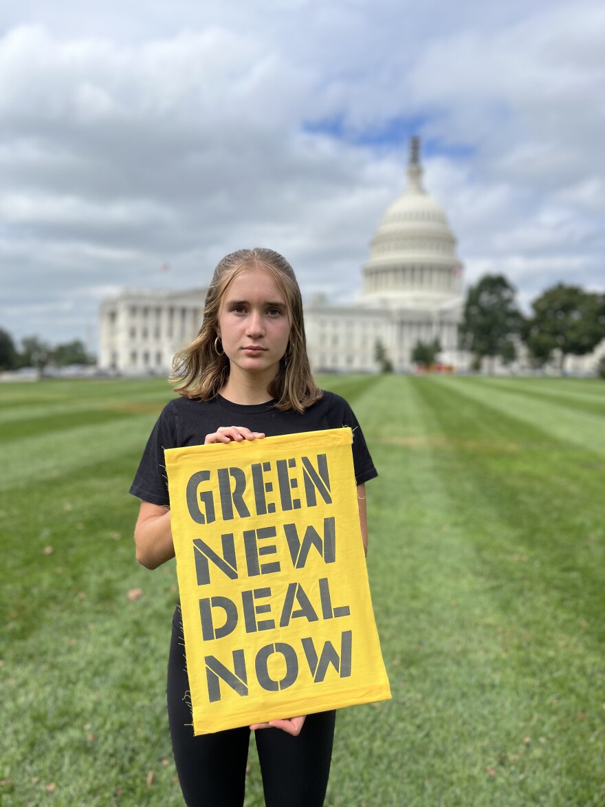 Molly Weber holds a sign that reads "Green New Deal Now" on the White House lawn. 