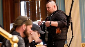 William Null (R) stands in the gallery of the Michigan Senate Chamber during the American Patriot Rally on the steps of the Michigan State Capitol in Lansing, Michigan. Others are unidentified. The Nulls were charged for their alleged roles in the plot to kidnap Gov. Gretchen Whitmer, according to the FBI.