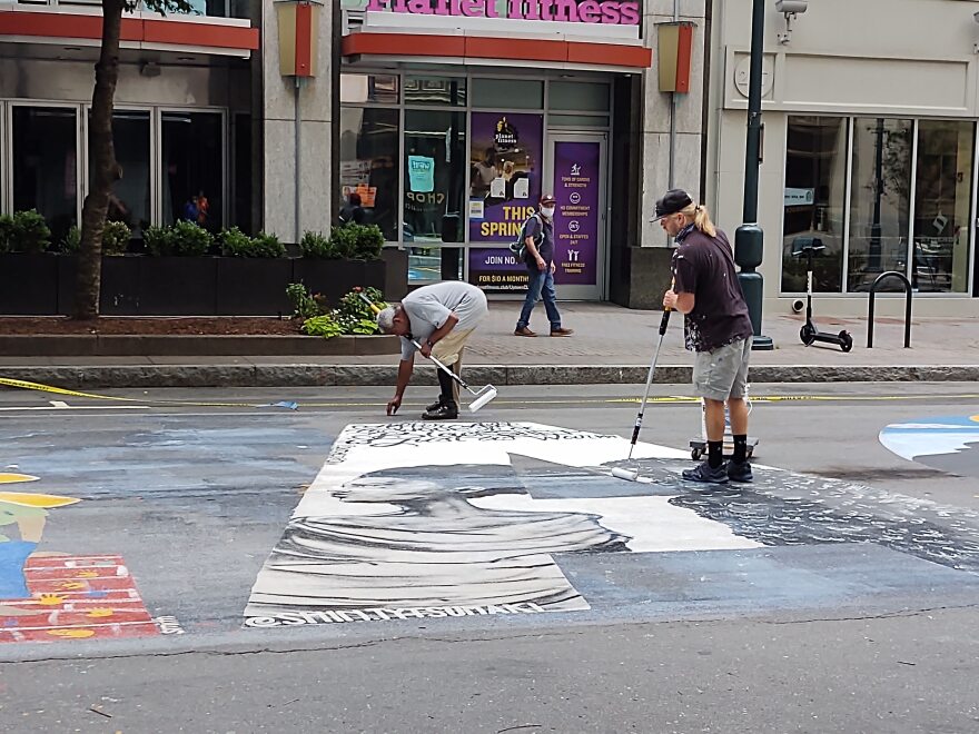 Workers apply sealant to letters in the Black Lives Matter mural on South Tryon Street Thursday. The city has extended the street closure through Sept. 30. 