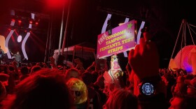 A nighttime shot of a Treefort Music Fest concert with the Festival Fairy sign sticking above the crowd. The picture is bathed in red from the stage lighting. 