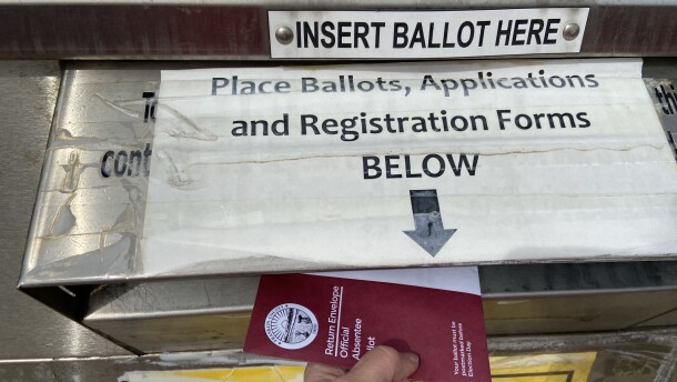 A voter returns an absentee ballot