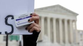 An abortion-rights activist holds a box of mifepristone pills as demonstrators from both anti-abortion and abortion-rights groups rally outside the Supreme Court in Washington, March 26, 2024.