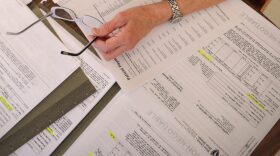 A person sitting at a table overlooks multiple medical bills.