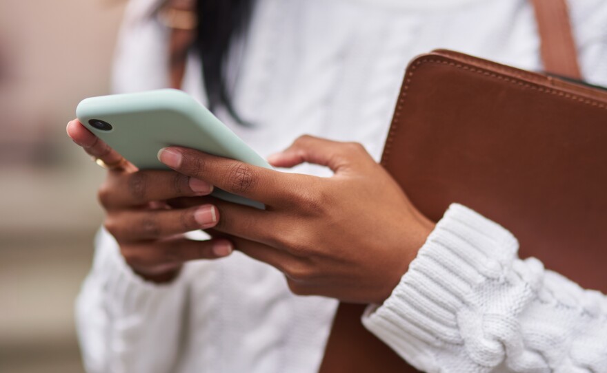 This stock image shows a female student holding a smartphone in her hands.
