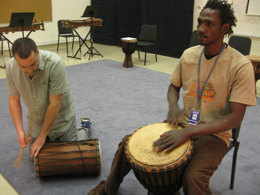 Teacher Paul Chandler (left) and musician Siaka Doumbia play <em>djembe</em> drums during music class.