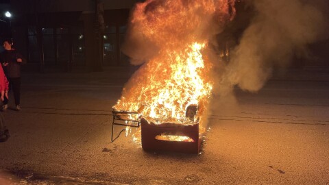 A burning piece of furniture sits in the street.