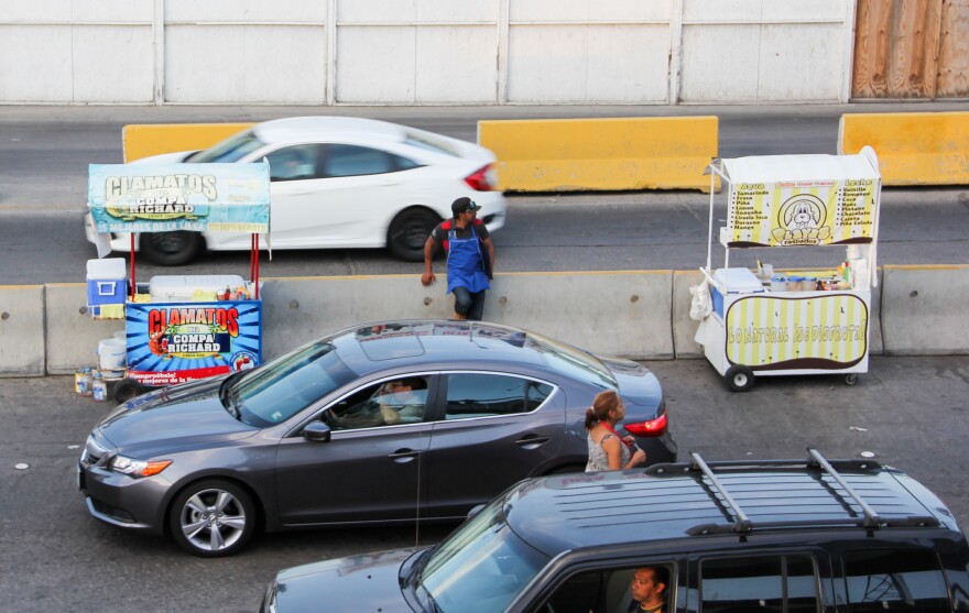 A Tijuana border food vendor takes a break from selling <em>Clamatos preparados</em>, a drink that includes Clamato juice, Worcester Sauce, clams, and hot sauce.